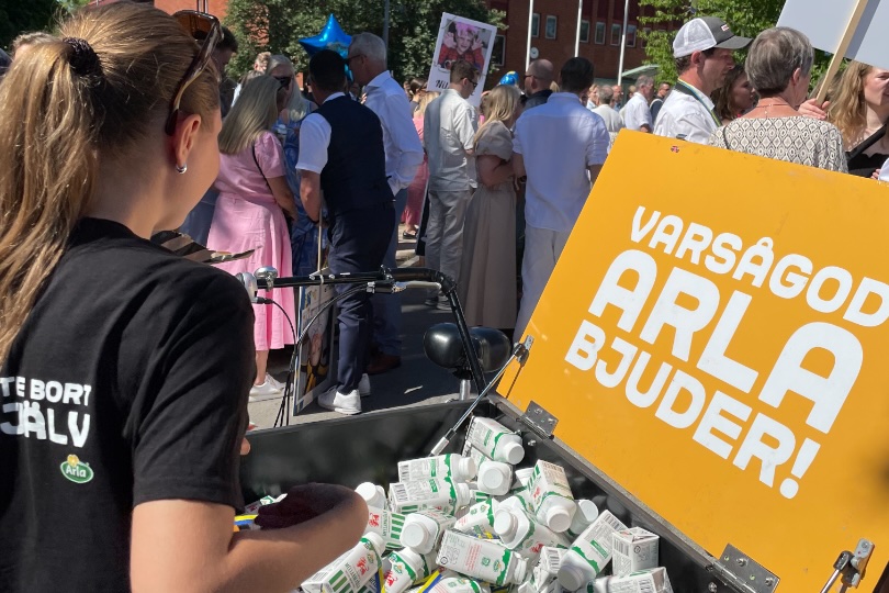 Handing out products from an orange Arla box in a crowd