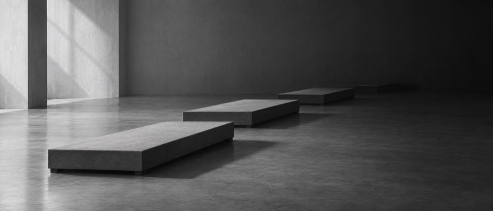 Photograph, greyscale: four narrow runway platforms receding in a row, the fourth dissolving into shadow