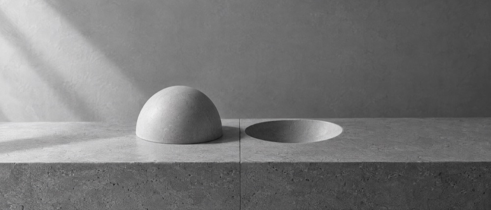 Photograph, greyscale: a smooth pale dome beside the identical hollow pressed into the stone, mirrored across a seam